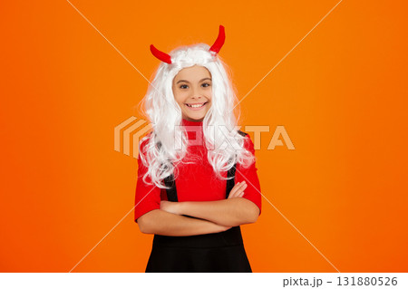 Girl devil in Halloween costume isolated on orange. Trick or treat. All Hallows costume party celebration. All Hallows devil. Imp horns. Girl in Halloween imp costume. Happy Halloween. Wicked grin 131880526