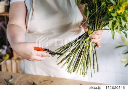 Florist trimming bouquet stems with shears in a floral workshop. Handmade floral craftsmanship, sustainable floristry, small business creativity, artisan workspace Florist trimming bouquet stems with shears in a floral workshop. Handmade floral craftsmanship, sustainable floristry, small business creativity, artisan workspace 131880546