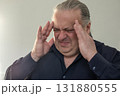 Close up portrait of a stressed man with headache and tension indoors 131880555
