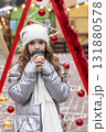 Girl in silver coat sipping coffee under festive Christmas decorations at a winter outdoor festival 131880578
