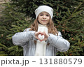 Young girl in a winter coat and scarf making a heart shape with her hands 131880579