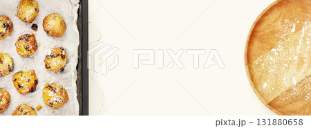 Eco friendly food banner with hande made natural sweet pastry on a baking sheet with wooden plate on a white background with copy space. Home made cookies with candied fruits and raisins. Flat lay Eco friendly food banner with hande made natural sweet pastry on a baking sheet with wooden plate on a white background with copy space. Home made cookies with candied fruits and raisins. Flat lay 131880658