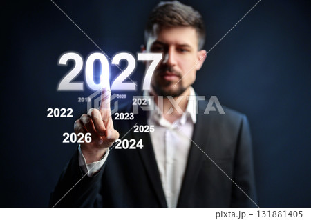 Man in a suit interacts with futuristic year display in a tech-inspired setting Man in a suit interacts with futuristic year display in a tech-inspired setting 131881405