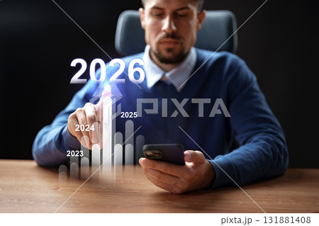 Man analyzing growth trends on smartphone while seated at desk in 2023 131881408