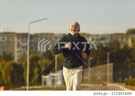 Happy joyful senior man running on city street during his outdoor sports workout Happy joyful senior man running on city street during his outdoor sports workout 131881699