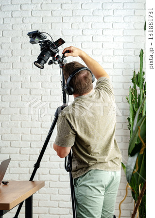 Creative professional adjusts camera setup in modern workspace for video recording Creative professional adjusts camera setup in modern workspace for video recording 131881731