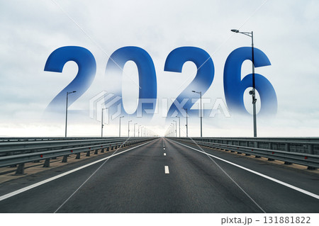 Road leading into the distance with 2026 displayed in blue against a cloudy sky Road leading into the distance with 2026 displayed in blue against a cloudy sky 131881822