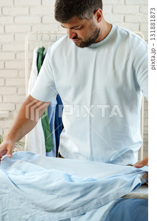 Man folding light blue fabric in a modern indoor setting during daylight hours 131881873