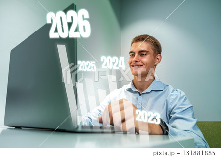 Young man working on a laptop while forecasting future trends in a modern office setting Young man working on a laptop while forecasting future trends in a modern office setting 131881885