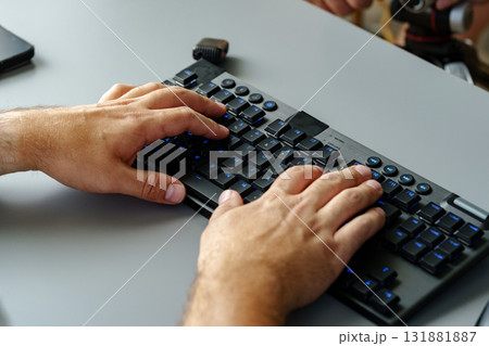 Hands typing on a modern keyboard in a workspace setting during daylight hours 131881887