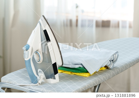 Ironing clothes on an ironing board in a bright room during the day Ironing clothes on an ironing board in a bright room during the day 131881896