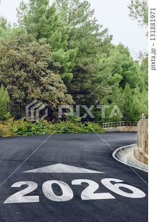 Curved road ahead with clear indication of the year 2026 surrounded by lush greenery 131881971