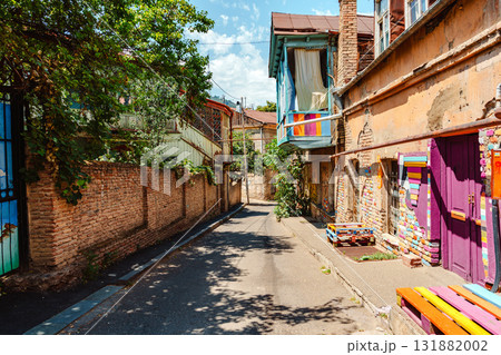 Colorful street in a historic neighborhood filled with vibrant art and greenery during a sunny day 131882002