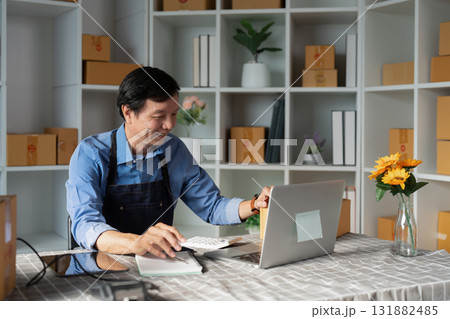 Cheerful small business owner working on a laptop and managing e-business tasks in a vibrant startup workspace 131882485