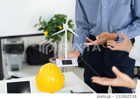 Innovation and Renewable Energy. An engineer showcasing a wind turbine model during a project discussion on sustainability. 131882538