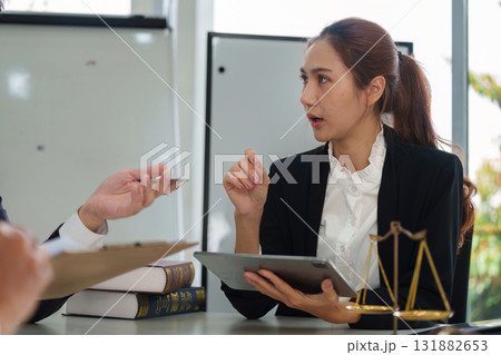 Legal Analysis and Client Interaction. A female lawyer discussing case details with a client in a professional environment. Legal Analysis and Client Interaction. A female lawyer discussing case details with a client in a professional environment. 131882653