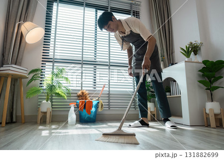 Home Cleaning and Organization. A skilled individual meticulously sweeping the floor, contributing to a well-maintained home environment. 131882699