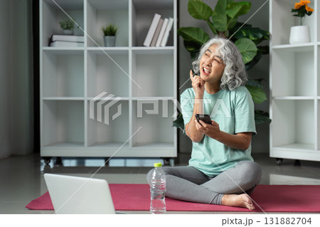 Wellness and Mindfulness. A senior woman engaging in daily wellness practices while enjoying a moment of reflection with her phone. 131882704