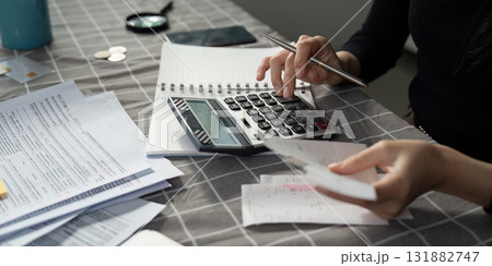 Individual calculating expenses with a calculator and receipts on a table Individual calculating expenses with a calculator and receipts on a table 131882747