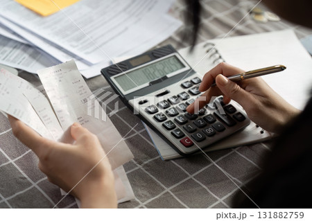 Individual calculating expenses using a calculator and receipts on a table Individual calculating expenses using a calculator and receipts on a table 131882759