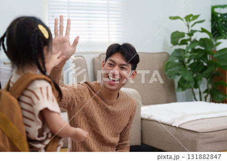 Joyful Goodbyes and Support. A father shares a joyful high-five with his daughter as she prepares for school. Joyful Goodbyes and Support. A father shares a joyful high-five with his daughter as she prepares for school. 131882847