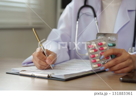 Record Keeping and Pharmaceutical Review. A healthcare professional examines medication while documenting patient information. Record Keeping and Pharmaceutical Review. A healthcare professional examines medication while documenting patient information. 131883361