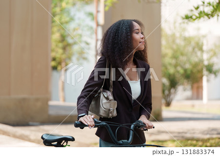 Sustainable Transportation and Eco-Friendly Lifestyle. A woman with a bicycle enjoying the outdoors, promoting green commuting. 131883374