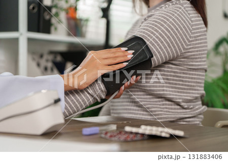 Health Monitoring and Care. A healthcare professional measures a patient's blood pressure, ensuring thoroughness in patient care. 131883406