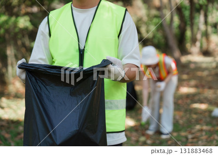 Volunteer Efforts in Environmental Cleanup. A participant shows dedication to sustainability while collecting trash in a park. Volunteer Efforts in Environmental Cleanup. A participant shows dedication to sustainability while collecting trash in a park. 131883468