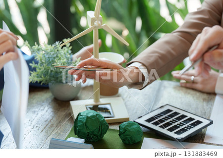 Sustainable Solutions and Innovation. A group brainstorming on environmental initiatives while reviewing renewable energy tools. 131883469