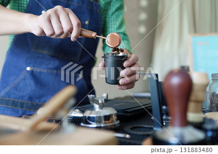 Sustainable Coffee Practices and Entrepreneurship. A dedicated barista meticulously measures coffee grounds for a perfect brew. Sustainable Coffee Practices and Entrepreneurship. A dedicated barista meticulously measures coffee grounds for a perfect brew. 131883480