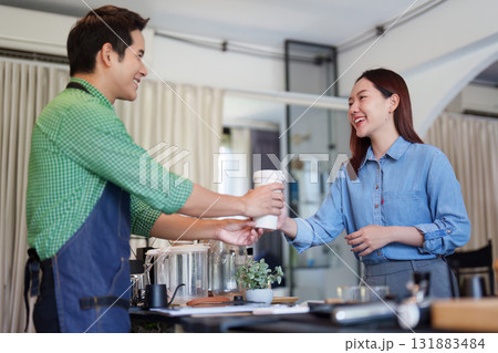 Sustainable Entrepreneurship and Customer Engagement. A barista serves a customer in an eco-friendly cafe focused on sustainability. 131883484