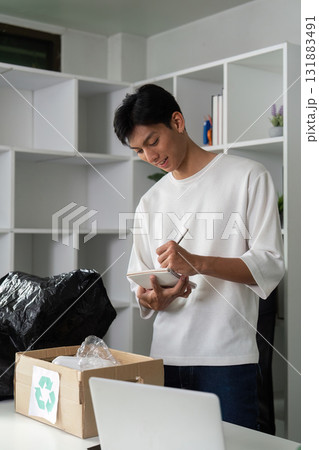 Eco-conscious Planning and Recycling. A person documenting items for recycling while promoting sustainable habits at home. Eco-conscious Planning and Recycling. A person documenting items for recycling while promoting sustainable habits at home. 131883491