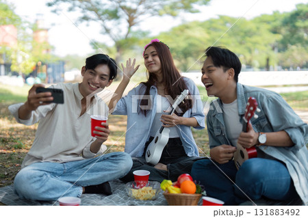 Friends taking selfies during a joyful picnic in the park 131883492