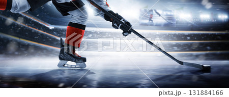 Hockey player on the rink at high speed. Close-up of hockey skates, stick, and puck on a skating rink. The large ice hockey arena is full of fans. Ice 131884166