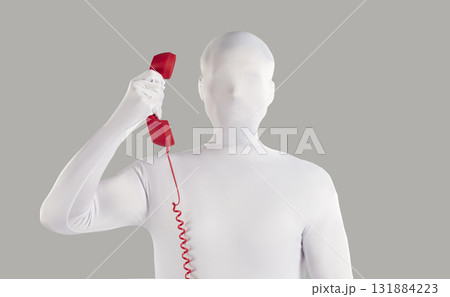 Man in faceless white bodysuit costume makes anonymous call from landline telephone Man in faceless white bodysuit costume makes anonymous call from landline telephone 131884223