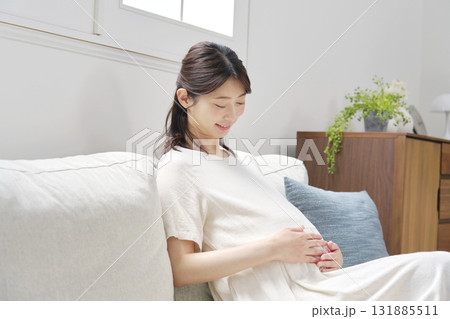 ソファーに座ってお腹を触る妊婦 131885511