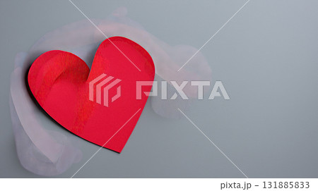 Red paper heart on gray background with soft translucent cloth adding romantic mood and textured detail, minimal composition evoking love and tenderness Red paper heart on gray background with soft translucent cloth adding romantic mood and textured detail, minimal composition evoking love and tenderness 131885833