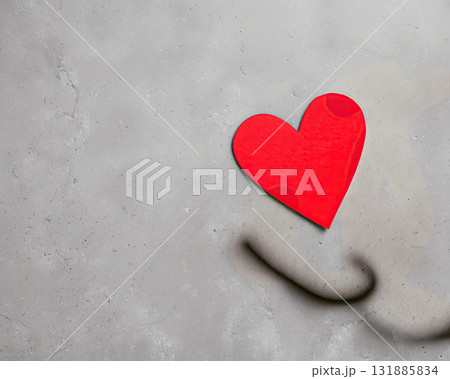 Red heart paper on concrete wall, shadow curve, minimal romantic still life, textured surface and soft contrast conveying gentle emotion 131885834