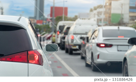 Rear side of white luxury car with turn on brake light. Traffic jam on the road. Many car queue up in traffic jams in the city at day time. 131886426