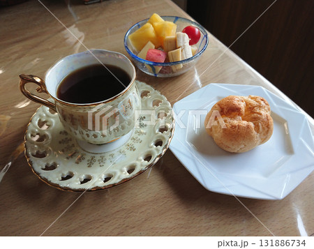 純喫茶で飲む一杯のブラックコーヒーとスィーツのセット (シュークリームとフルーツの小鉢盛り) 131886734