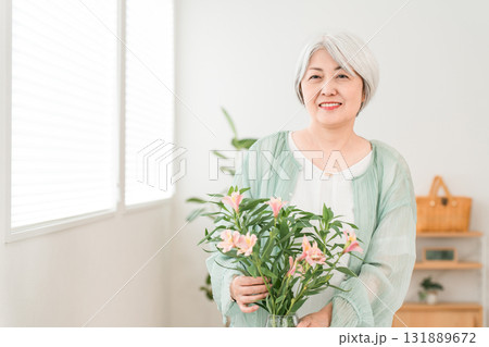 自宅のリビングで花をいけるシニア女性（フラワーセラピー,フラワーアレンジメント）） 131889672