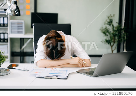 Asian woman feeling migraine head strain.Overworked businesswoman financier while working on laptop and tablet Asian woman feeling migraine head strain.Overworked businesswoman financier while working on laptop and tablet 131890170