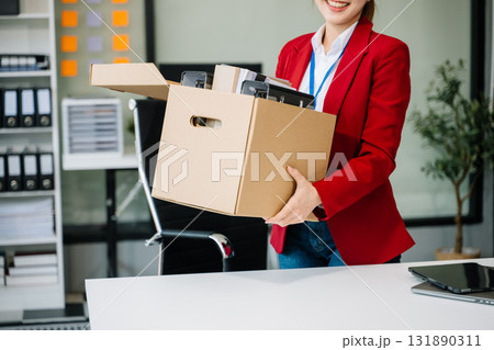 Happy and excited young beautiful Asian woman office worker celebrating her resignation, carrying her personal stuff. 131890311