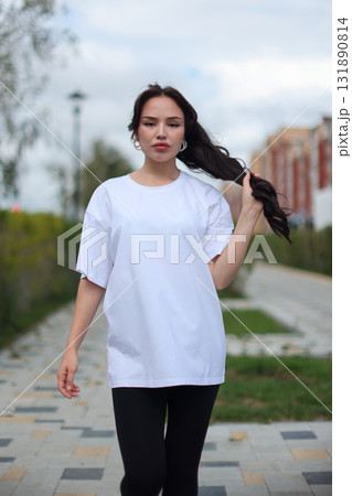 A Stylish Young Woman Dressed in an Oversized White TShirt and Comfortable Leggings A Stylish Young Woman Dressed in an Oversized White TShirt and Comfortable Leggings 131890814