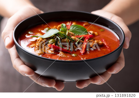 Thai food, Red curry with pork in black bowl holding by hand 131891820