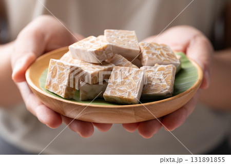 Tempeh made from fermented soybeans on wooden plate holding by hand, Traditional Indonesian food Tempeh made from fermented soybeans on wooden plate holding by hand, Traditional Indonesian food 131891855