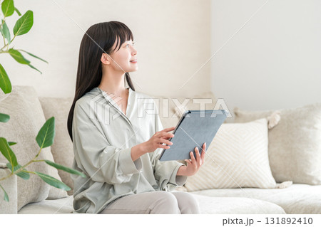 ソファーに座りながらタブレットを使う若いアジア人女性 131892410