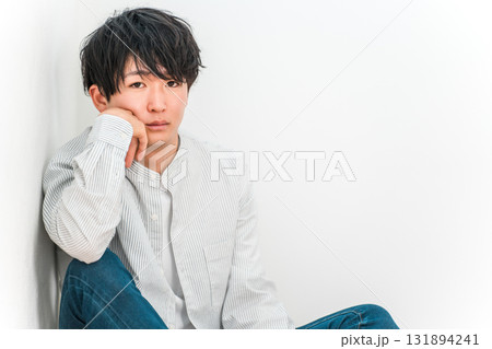 白い壁のリビングにあぐらで座る若いアジア人男性（クール,ハンサム,好青年） 131894241