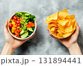 Unhealthy vs healthy food. vegetable salad and potato in different hands on green background . Choice between fast foods and vegetables, fruit. 131894441